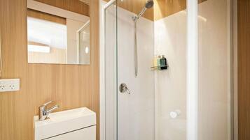 A modern bathroom with a glass-enclosed shower, a white sink, and a mirror above the sink.