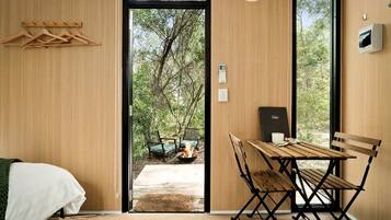 Une pièce avec un lit, une table et des chaises, un foyer extérieur et une vue sur les arbres.
