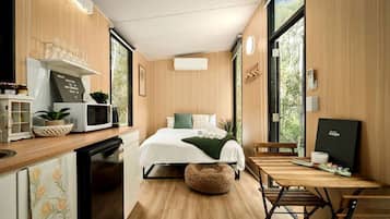 A compact bedroom with a bed, bedside table, and a window.
