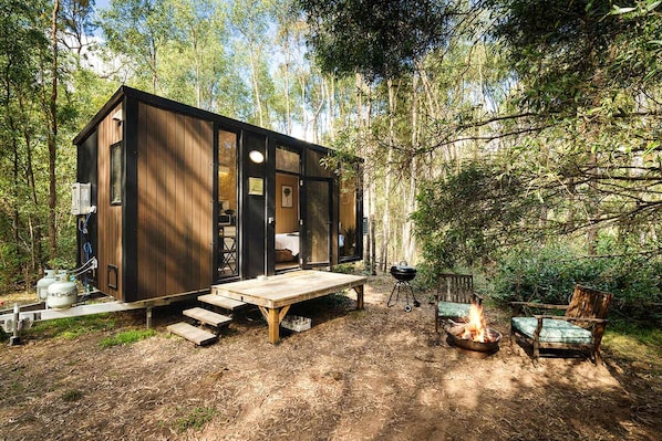 A wooden cabin with a deck, a fire pit, and outdoor seating.