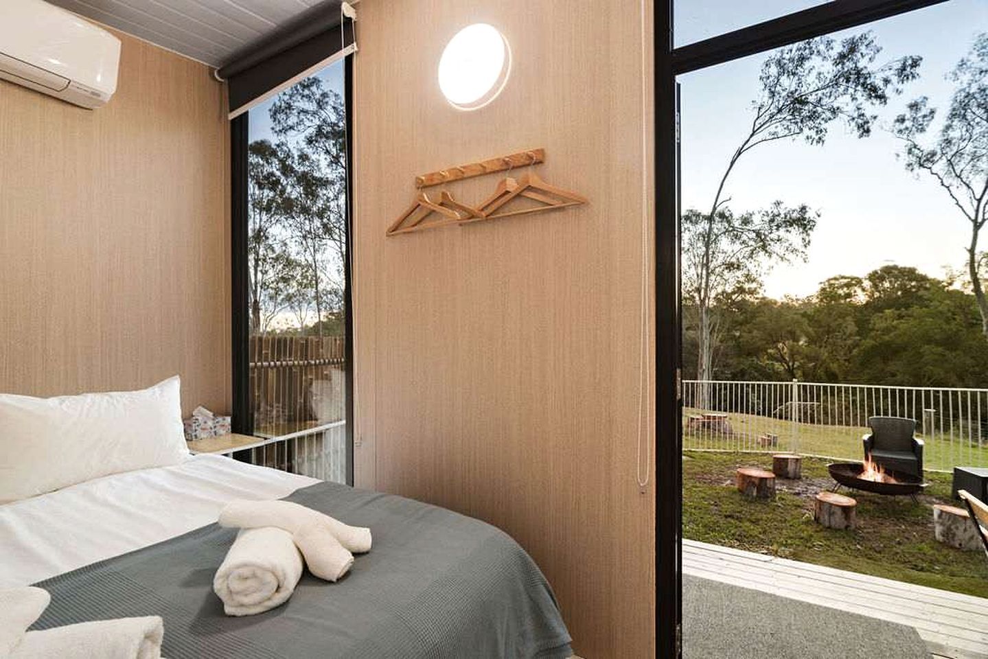 Un dormitorio con cama, un perchero de madera y vistas a un espacio exterior con una chimenea.