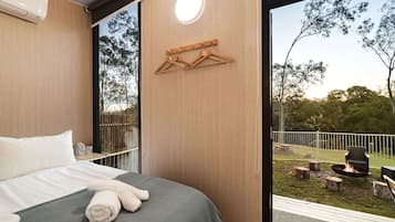 Un dormitorio con cama, un perchero de madera y vistas a un espacio exterior con una chimenea.