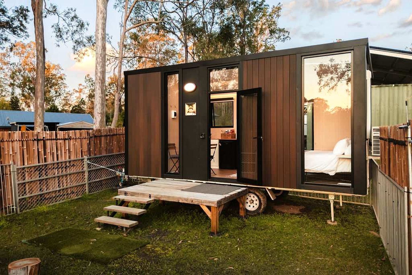 A small, modern cabin with a bed, a dining area, and a small kitchen.