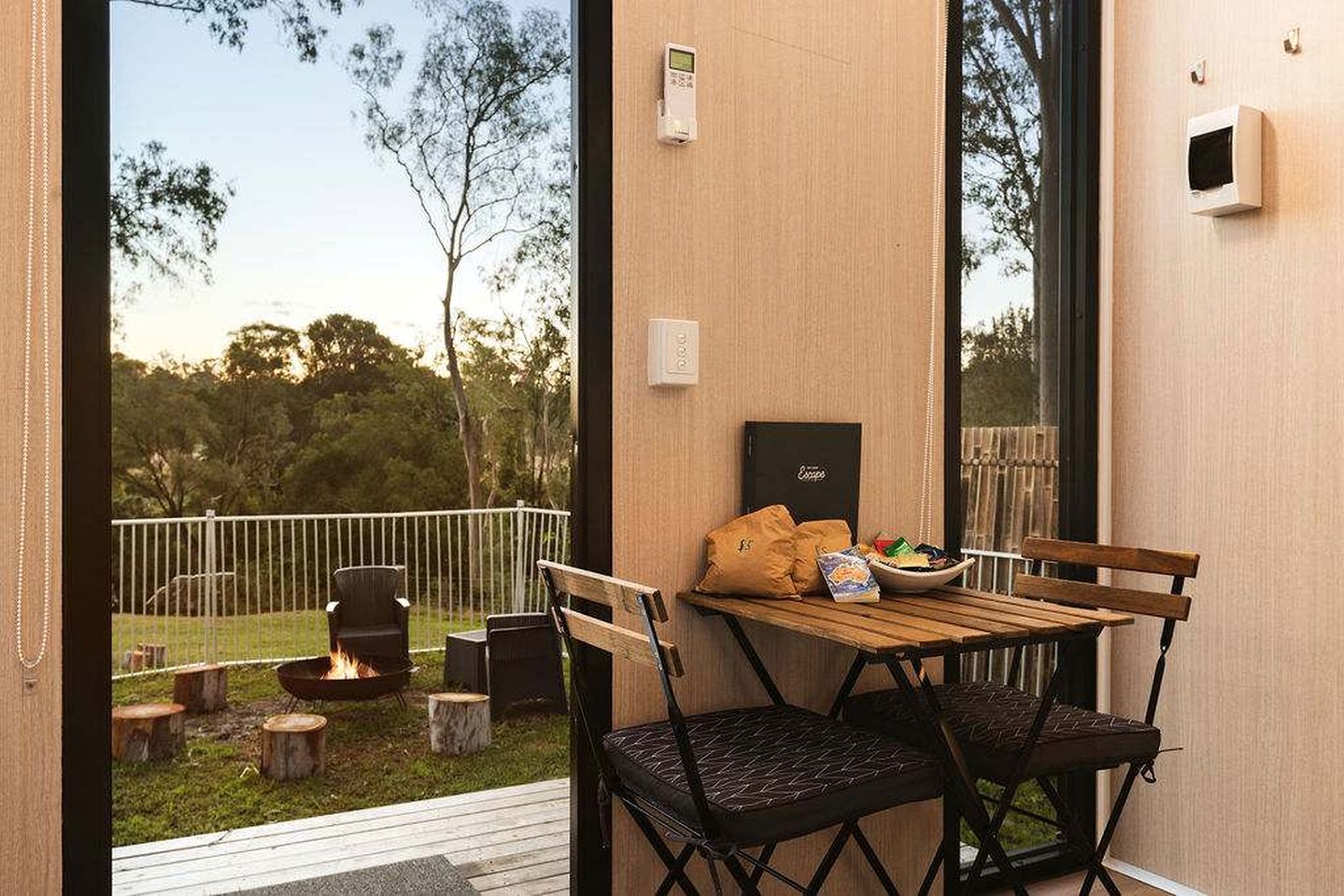 Área de estar externa com mesa, cadeiras e lareira.