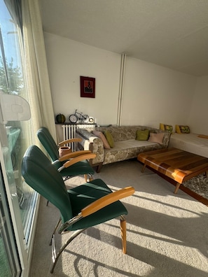 A living room with a sofa, two green armchairs, a wooden coffee table, and a radiator. - Lorik Studio Apartment (Prishtinë)