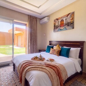 Ein Hotelzimmer mit einem großen Bett, einem Bild an der Wand und Blick ins Freie.