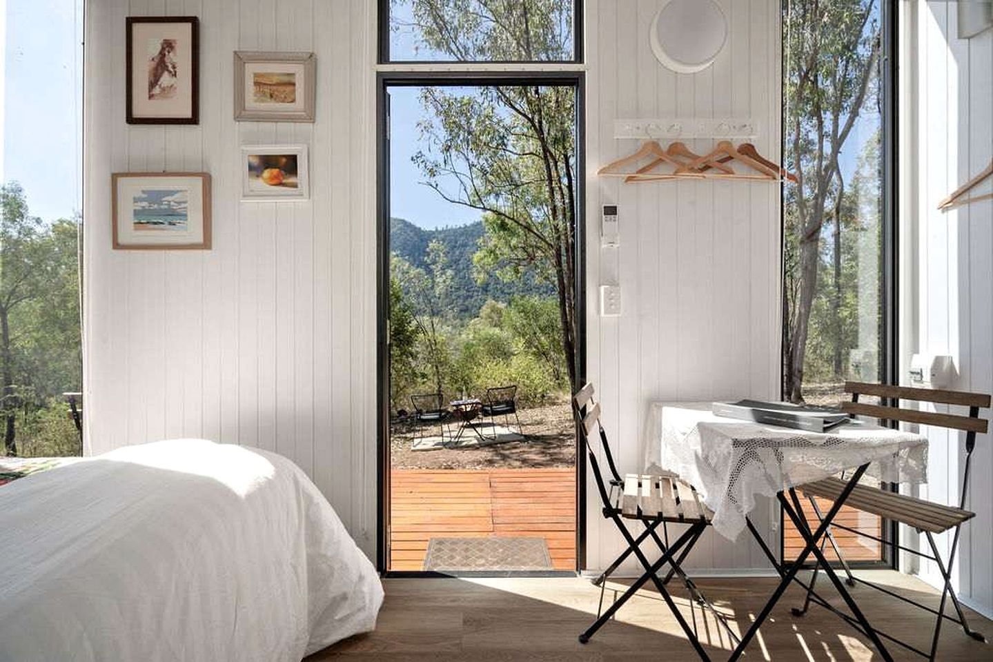 A bedroom with a bed, a table with chairs, and a view of the outdoors through a door.