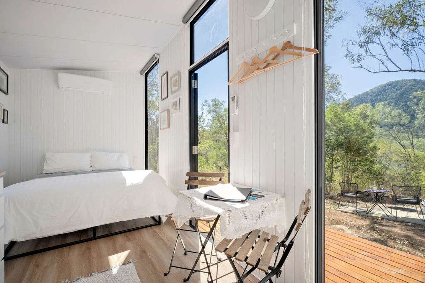 Ein Schlafzimmer mit einem Bett, einem Schreibtisch und Blick auf eine bewaldete Gegend.