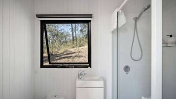 A bathroom with a window, a sink, and a shower.