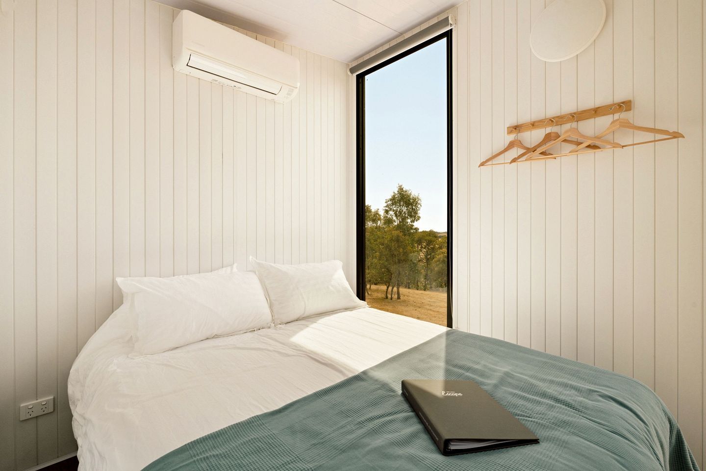 A bedroom with a bed, a window, and a wall-mounted air conditioner.