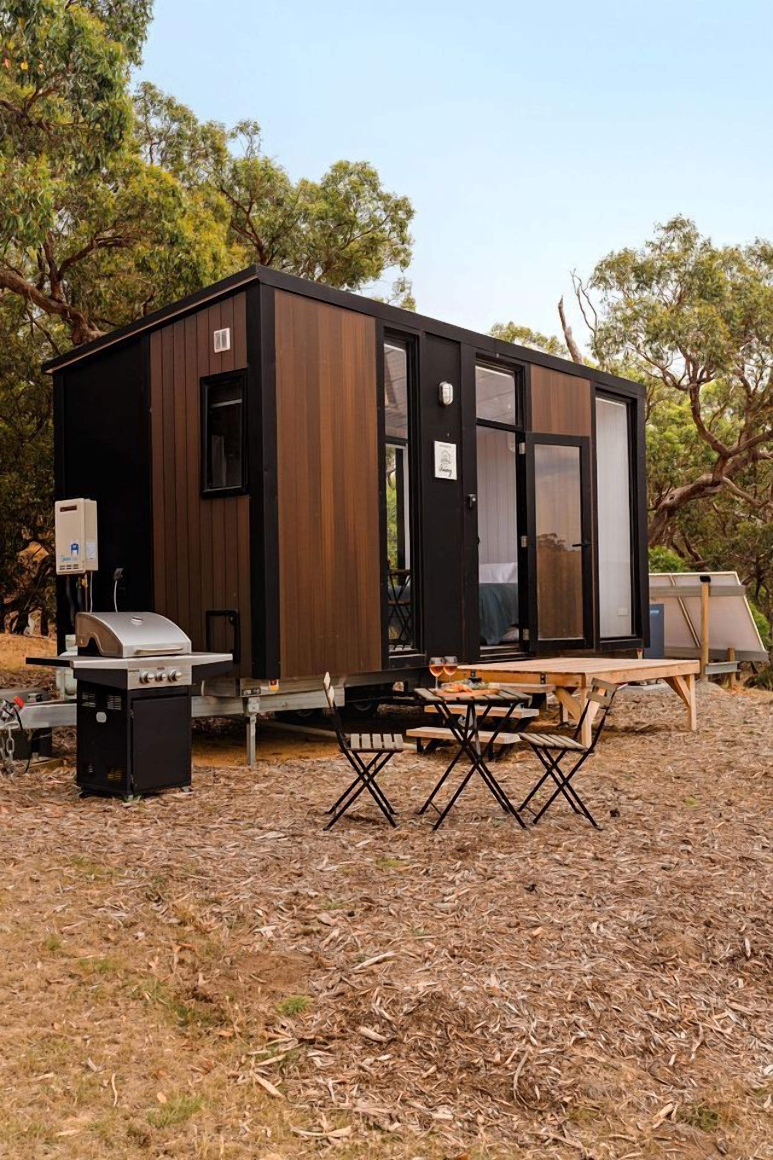Une cabane moderne et compacte, dotée d’un barbecue intégré et d’une table pour les repas en plein air.