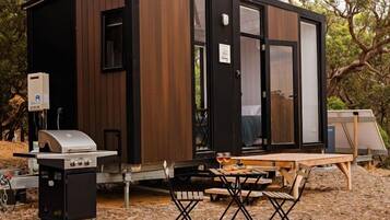Une cabane moderne et compacte, dotée d’un barbecue intégré et d’une table pour les repas en plein air.