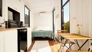 Une petite chambre comprenant un lit, une petite table et un coin cuisine.