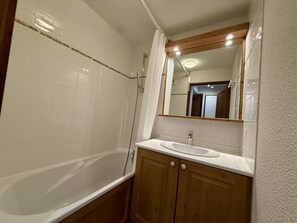 A bathroom with a bathtub, a sink, and a mirror. - Apartment with balcony and ski slopes view (Morillon)
