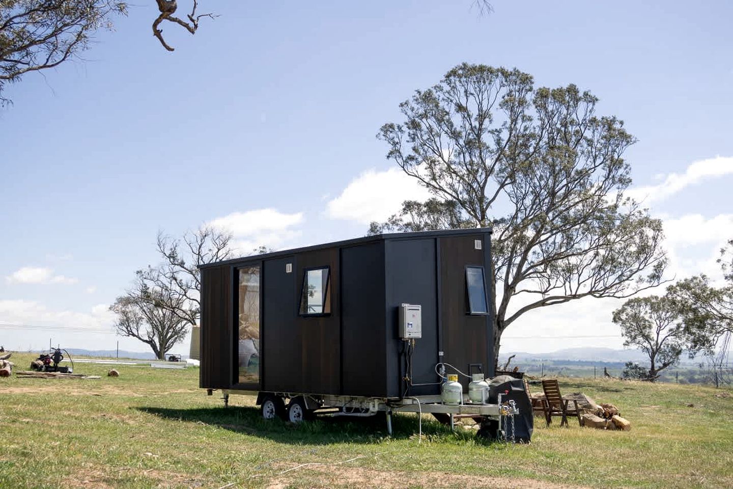 A small, dark-colored mobile home with a door, windows, and a flatbed trailer.