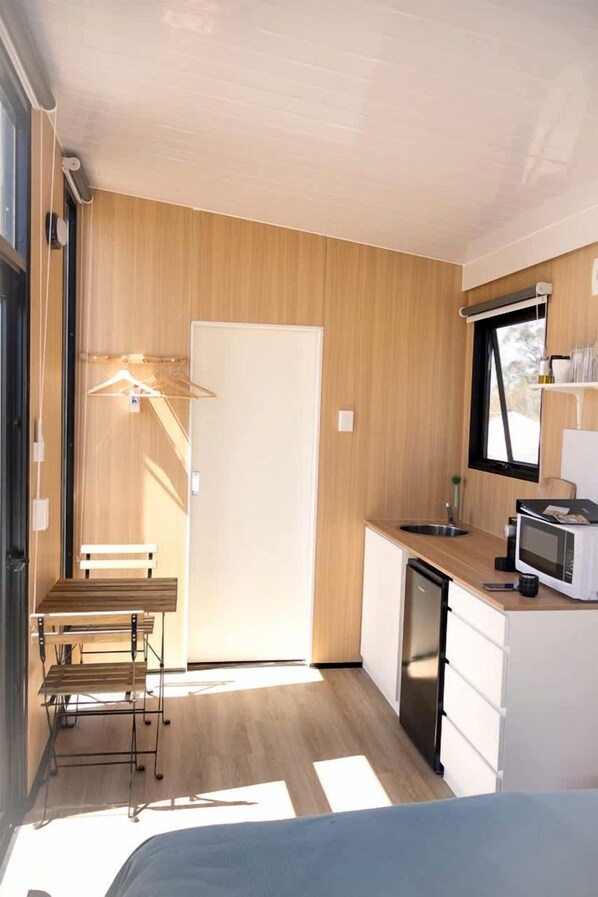 A compact kitchen with a microwave, sink, and wooden cabinets.