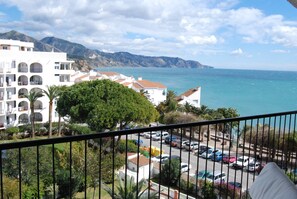 A coastal view with a building featuring balconies and a parking area in the foreground. - Apartment in Nerja Near Carabeillo Beach (Nerja)