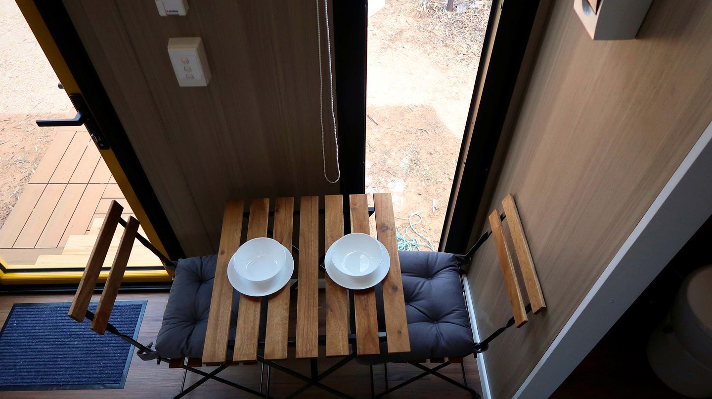 A small, enclosed space with a table and two chairs, a window, and a door.