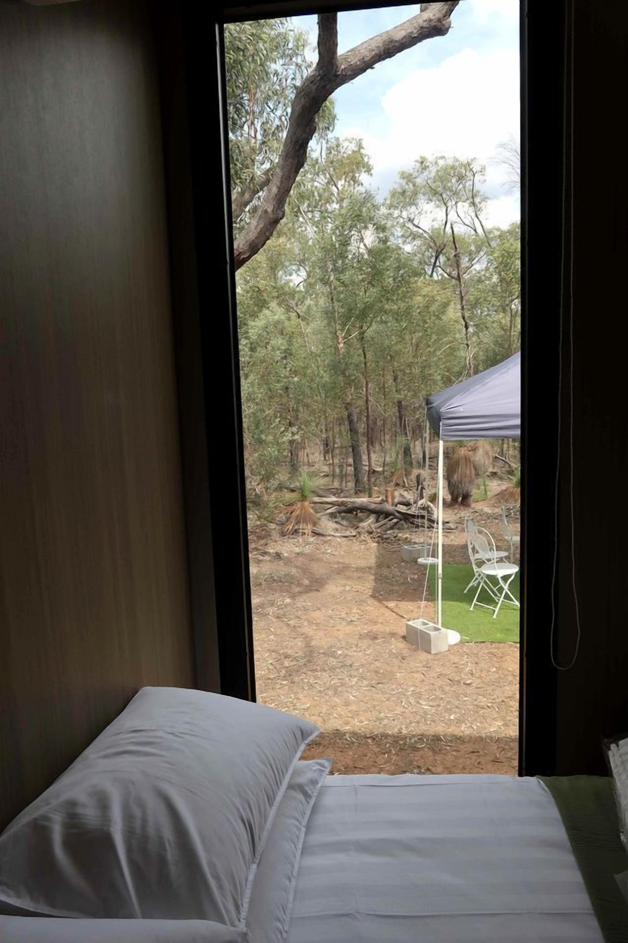 Une chambre avec un lit et une vue sur un espace extérieur comprenant une tente et des chaises.