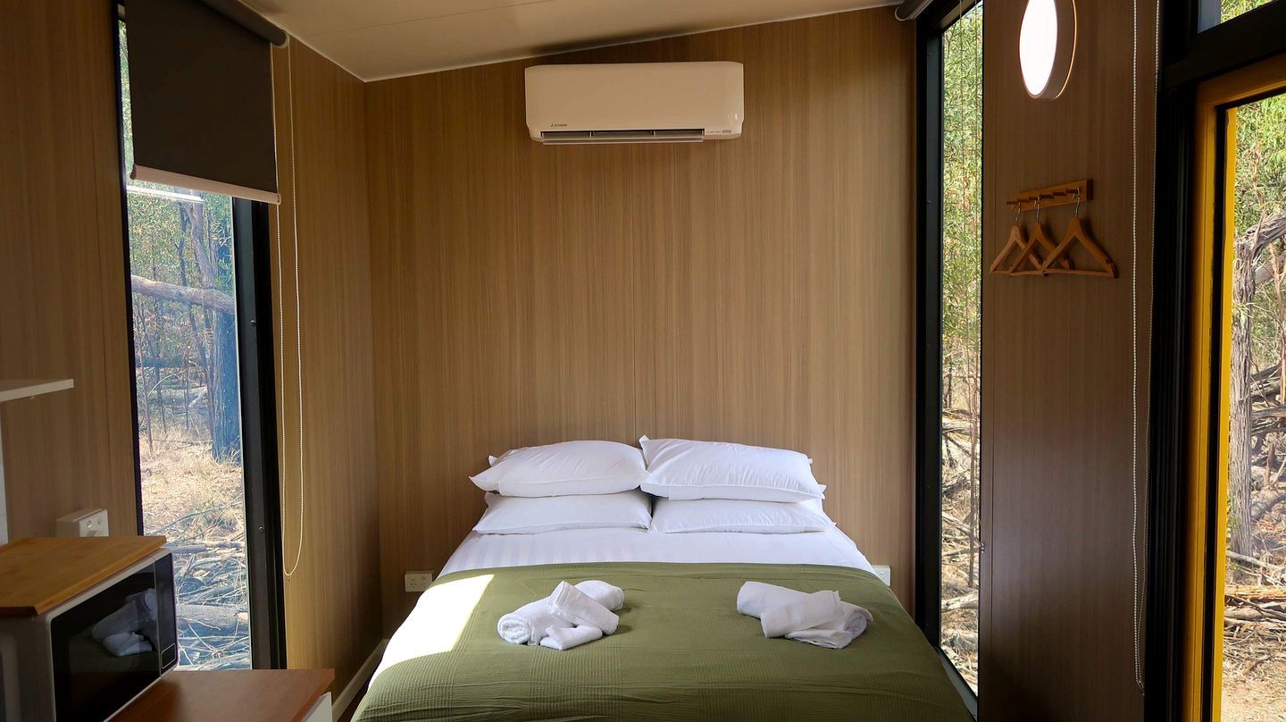 A hotel room with a bed, a window, and a wall-mounted air conditioner.