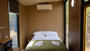 A hotel room with a bed, a window, and a wall-mounted air conditioner.
