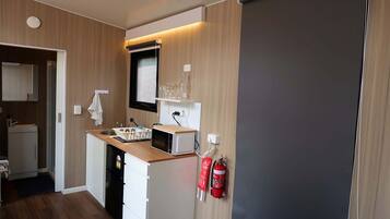 Une petite cuisine équipée d’un four à micro-ondes, d’un évier et de placards de rangement.