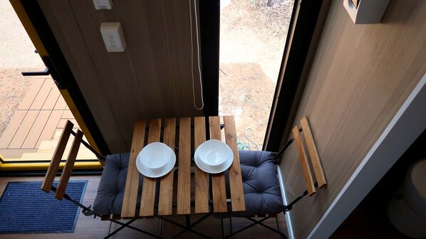 Un petit espace clos comprenant une table, deux chaises, une fenêtre et une porte.