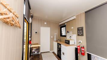 A compact kitchen with a microwave, sink, and a small window.