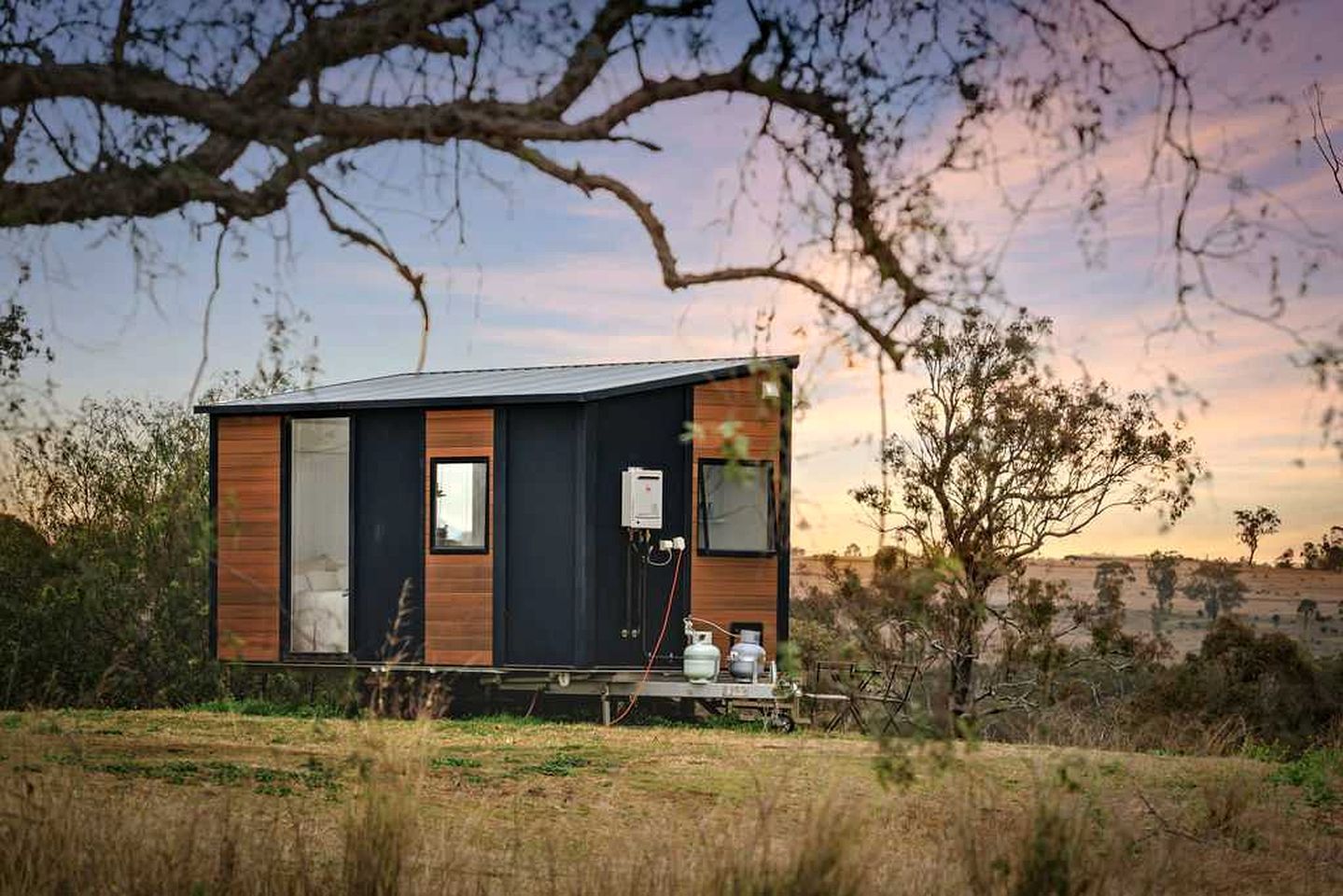 A modern, single-story cabin with a large window, a door, and a small porch area.