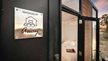 A sign indicating the property is managed by Away, with a view of a bedroom through a glass door.