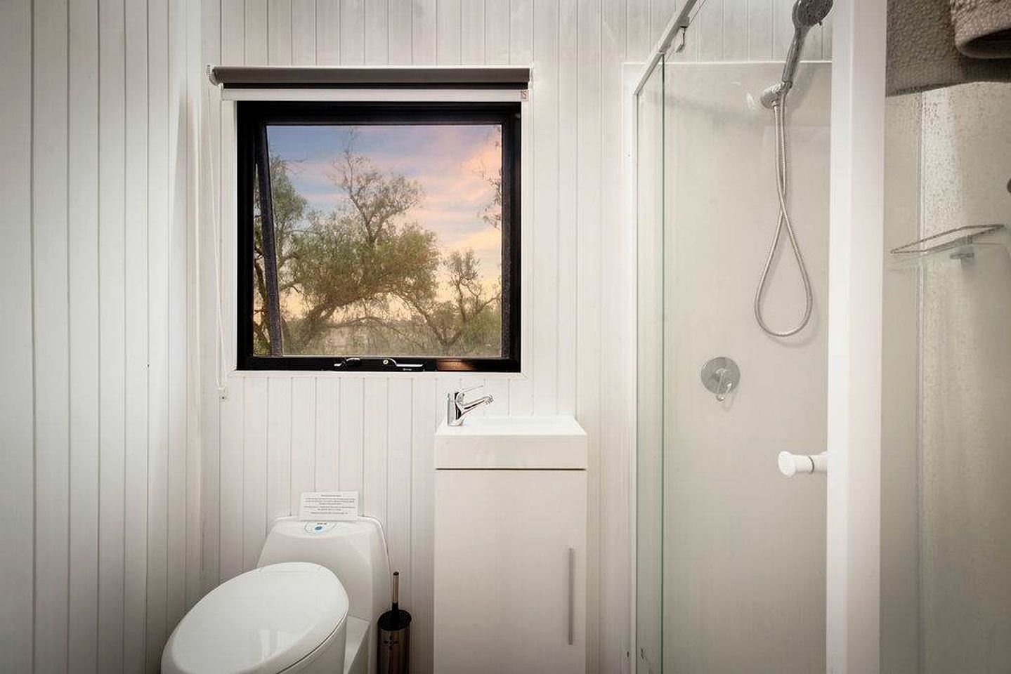 Une salle de bain avec une fenêtre, des toilettes, un lavabo et une douche.