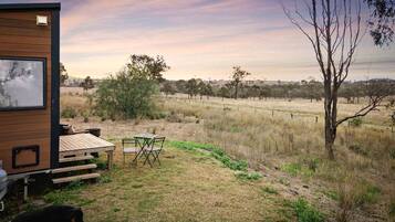 A wooden cabin with a deck, a table, and chairs outside.