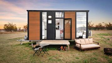 A modern mobile home with a kitchen, a sleeping area, and a small outdoor seating area.