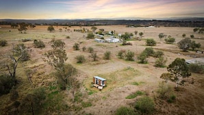 A rural landscape with a small house surrounded by trees and open fields. - Charming Tiny House with Panoramic Views of the Valley in Queensland, Australia (Goombungee)