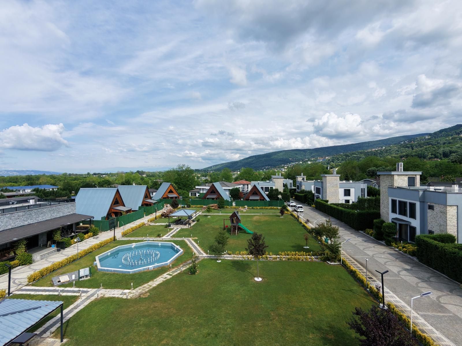 A residential area with modern houses, a swimming pool, and a well-maintained lawn.