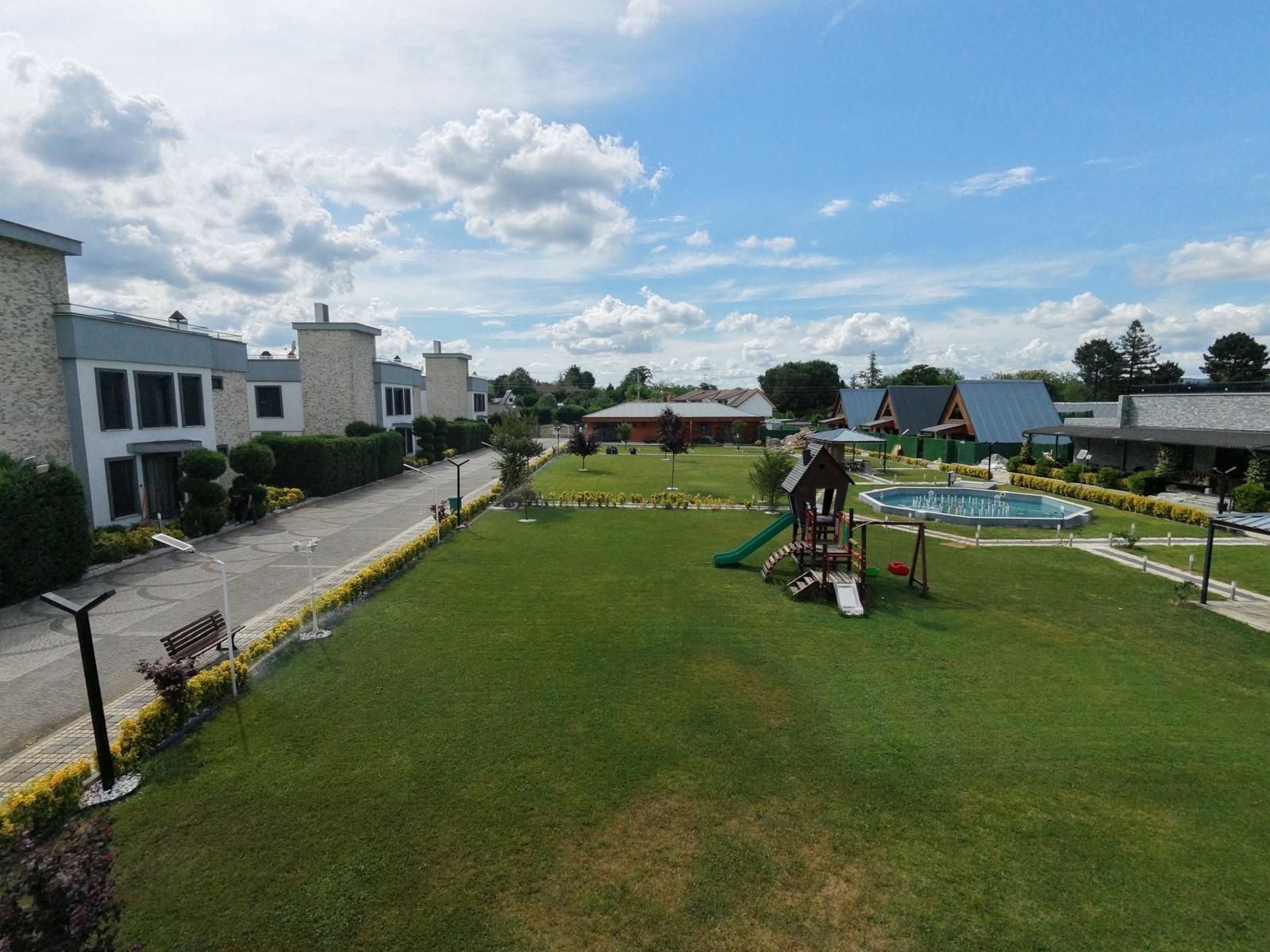 A residential area with a playground, a swimming pool, and houses with modern architecture.