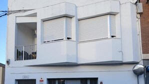 A two-story building with a garage door, a balcony, and a visible address number. - Apartment 'Lo Raco Del Delta' with Private Terrace, Wi-Fi and Air Conditioning (Sant Jaume d'Enveja)