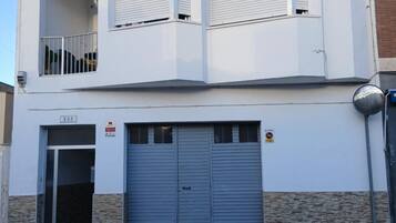 En tvåvåningsbyggnad med en garageport, en balkong och ett tydligt synligt husnummer.