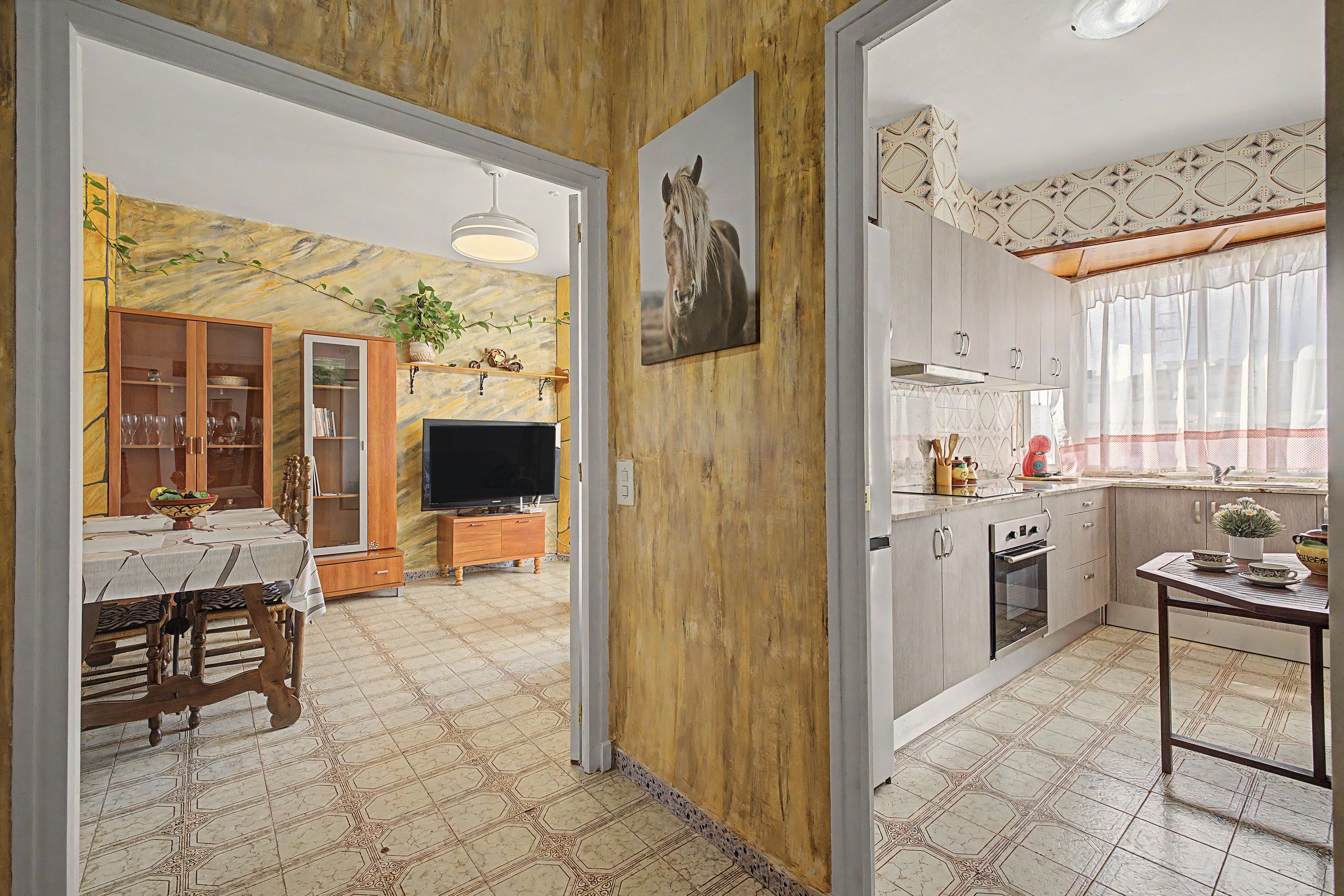 Un comedor con una mesa preparada para dos, un televisor y un mueble de madera con puertas de cristal.