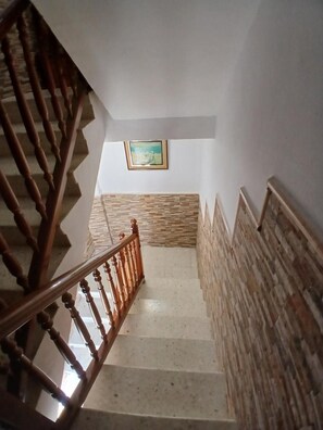 A staircase with wooden balusters and a patterned wall at the bottom.