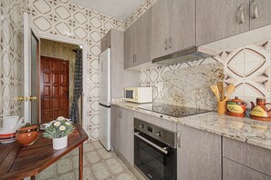 A compact kitchen with a microwave, oven, and wooden cabinets.