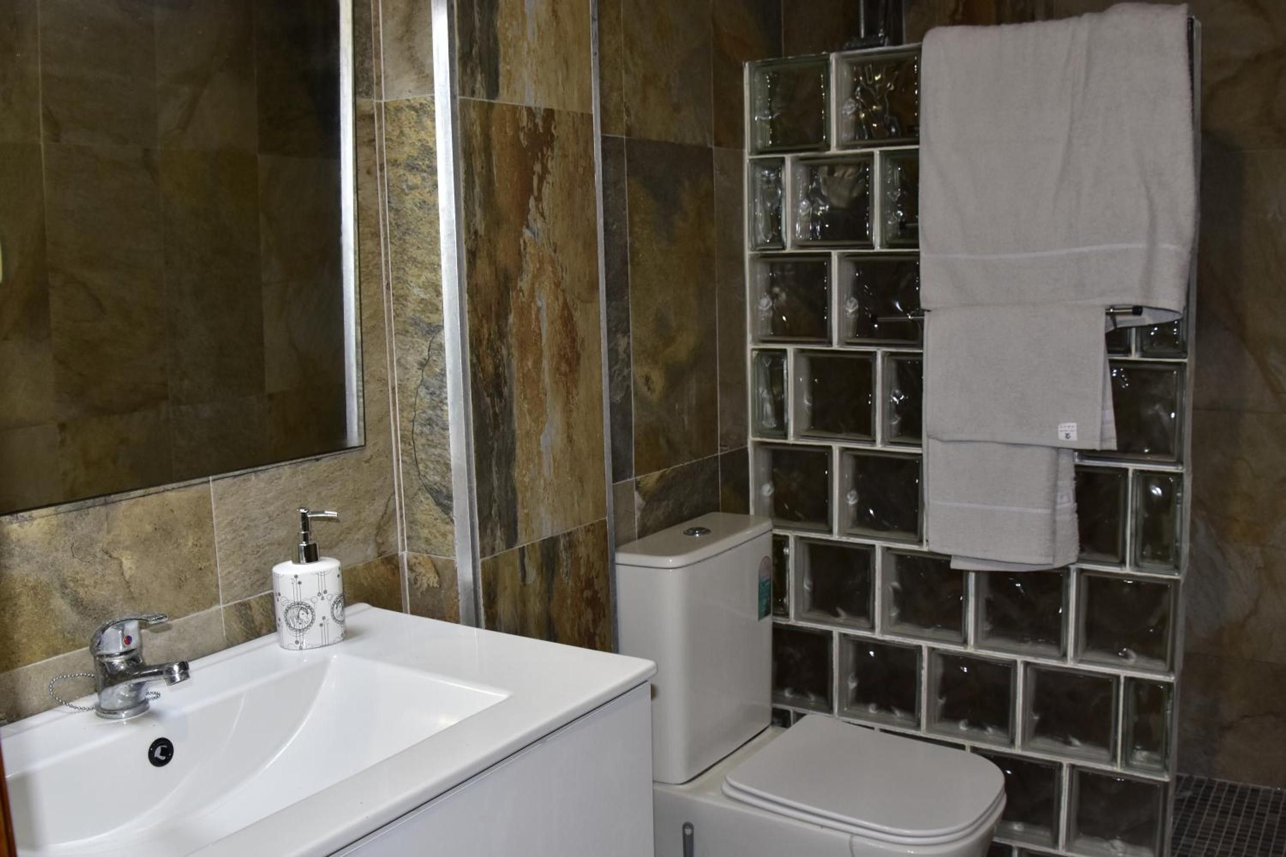 Un baño con lavamanos blanco, inodoro y cabina de ducha de vidrio.