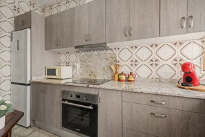 A kitchen with wooden cabinets, a built-in oven, a microwave, and a red coffee maker.