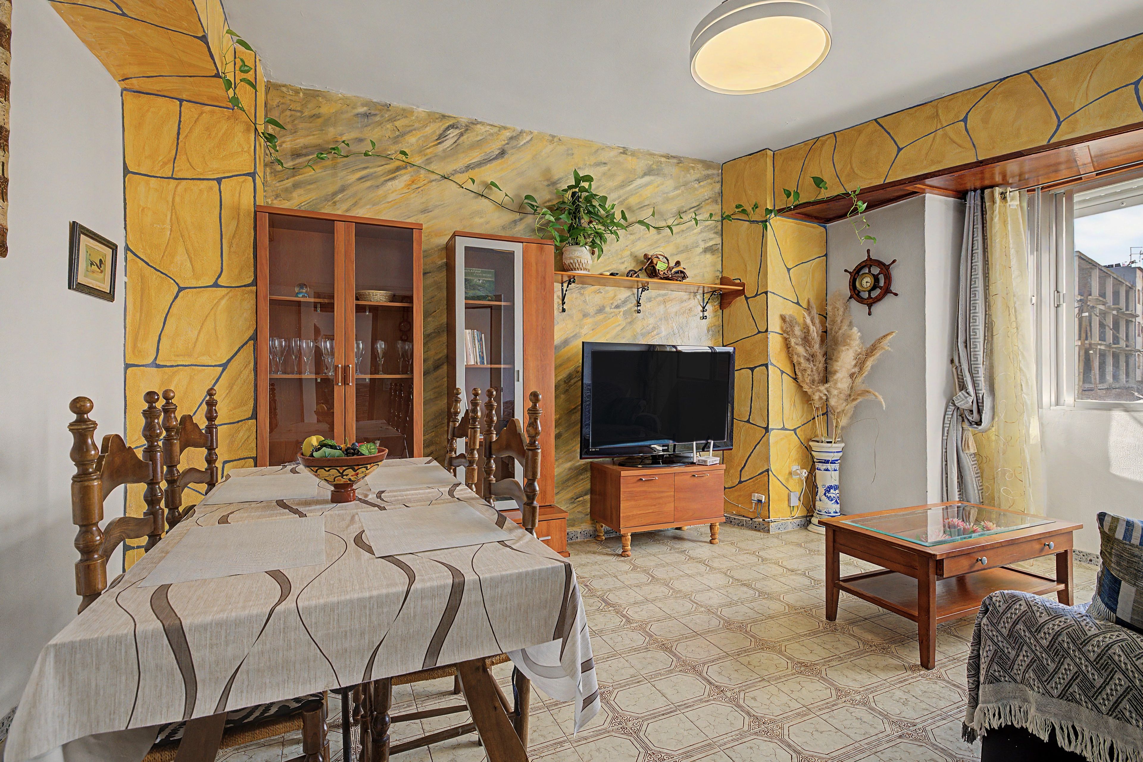 Una sala de estar con una mesa de comedor, sillas, un televisor y un sofá.