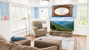 Ein Wohnzimmer mit Kamin aus Stein, einem großen Flachbildfernseher und einer gemütlichen Sitzecke.