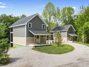 A two-story house with a covered porch and a gravel driveway. - Seaberry Woods | A Nature-Filled Retreat Near Camden (Hope)