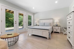 A bedroom with a bed, bedside tables, a dresser, and a round table with a chair. - Seaberry Woods | A Nature-Filled Retreat Near Camden (Hope)