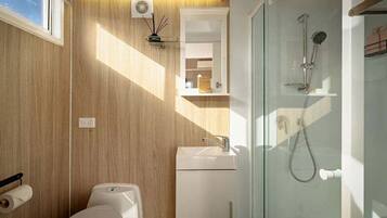 A modern bathroom with a wooden wall, a glass shower enclosure, a toilet, and a sink.