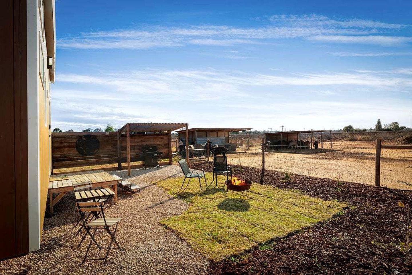 A patio with a grill, seating, and a fire pit.