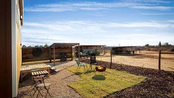 A patio with a grill, seating, and a fire pit.